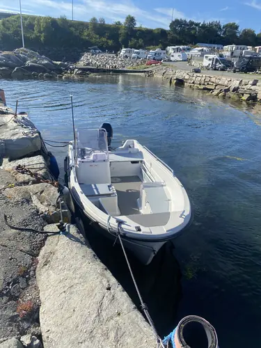 En båt fortøyd nedenfor plassene, med bobiler på land bak