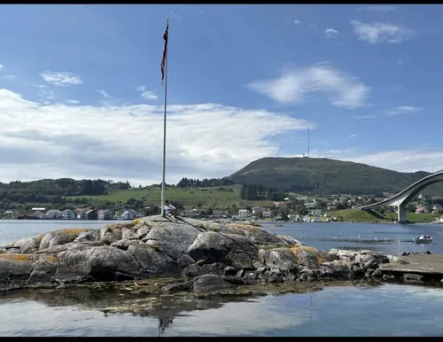 Flaggstanga på knausen utenfor campingplassen en sommerdag, med Boknbrua til høyre